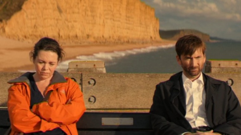 Olivia Coleman and David Tennant sitting by oceanside cliffs