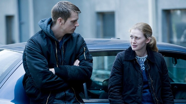 Joel Kinnaman and  Mireille Enos leaning on a car