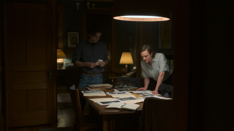 Wagner Moura and Elisabeth Moss standing over a table in Shining Girls