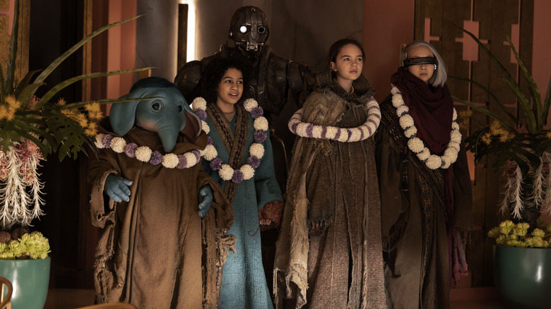 Neel, Wim, Fern, and KB arrive at a luxury resort wearing robes and necklaces in Star Wars: Skeleton Crew