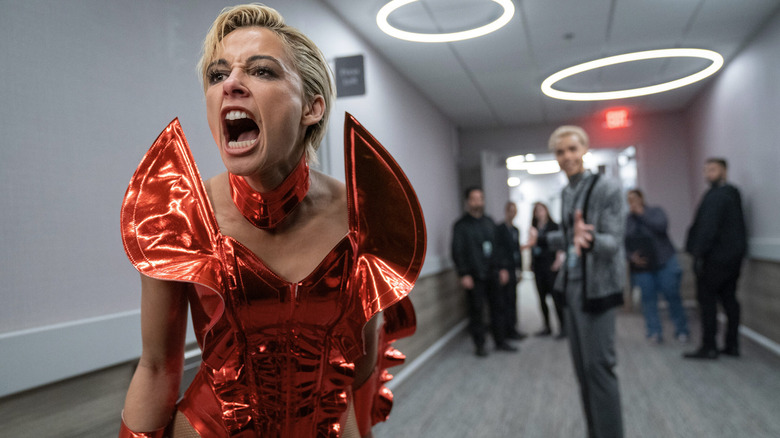 Clad in an ostentatious red dress, Skye Riley screams at someone off camera in a hallway in Smile 2