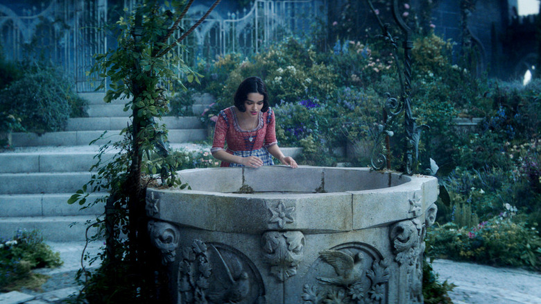 Rachel Zegler's Snow White peering into a wishing well.