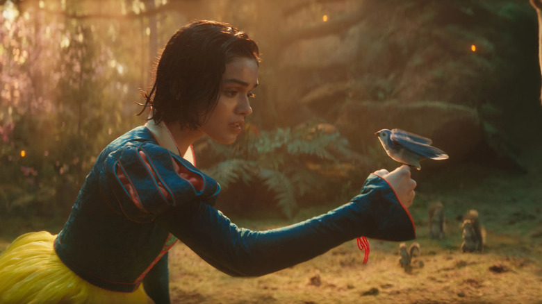 Snow White, kneeling, holding a bird in the woods. From Snow White.