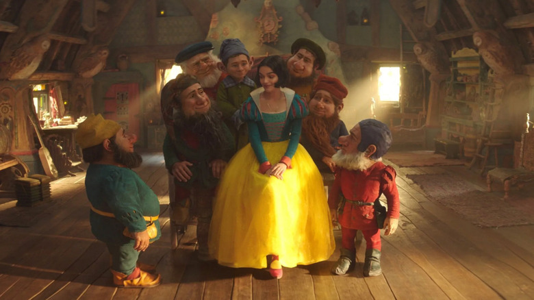 Snow White, sitting among the seven dwarfs, in their cabin in the woods. A shot from Snow White.