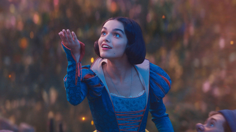 Snow White holding her right hand out in wonderment as fireflies float behind her in Snow White (2025)