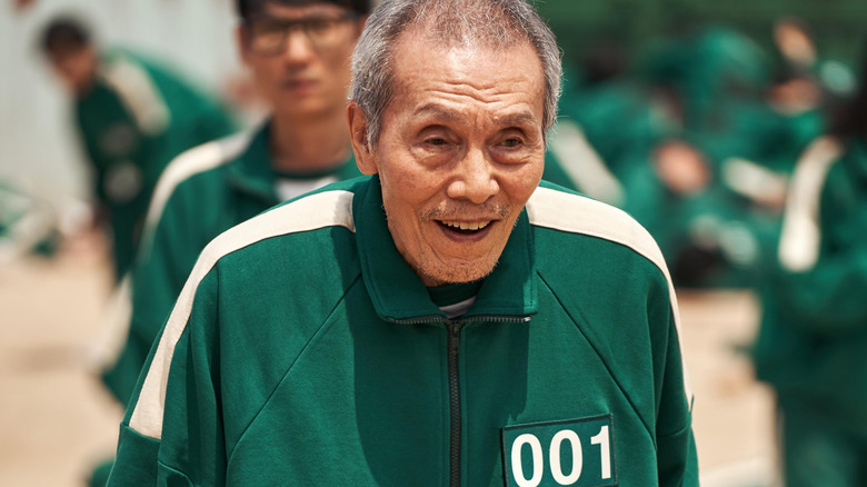 Il-nam smiles and puts on a tracksuit in the first season of the squid game