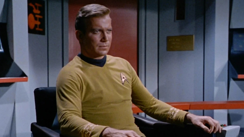 Kirk (William Shatner) sits in the captain's chair Star Trek: The Original Series