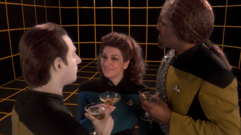 Data, Troji and Warf enjoy holodek champagne glasses.