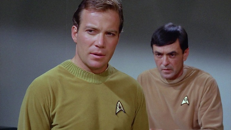 Captain Kirk and Scotty in the transporter room, wearing older uniforms in Star Trek