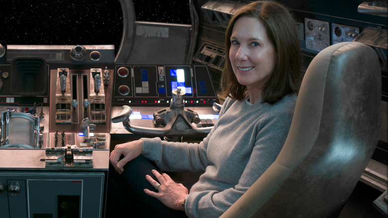 Kathleen Kennedy sitting at the controls of the Millennium Falcon in a behind-the-scenes still from Star Wars: The Force Awakens