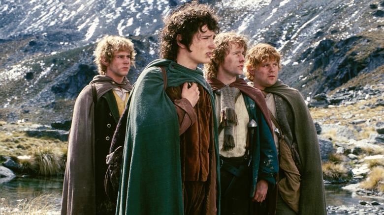 Four hobbits standing in front of a mountainrange in 