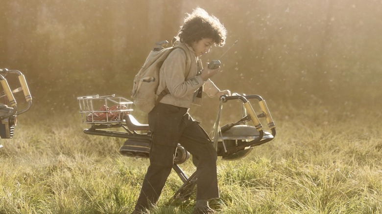 Wim walking through a field with his hoverbike in Star Wars: Skeleton Crew