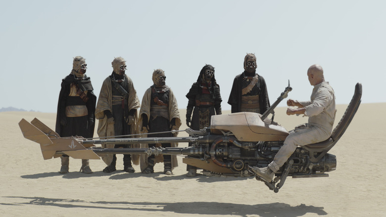 Boba showing a group of Tusken Raiders how to use a speeder in The Book of Boba Fett