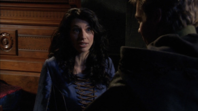 Claudia Black's Vala Mal Doran is talking to someone outside someone while wearing blue clothes in Stargate SG-1