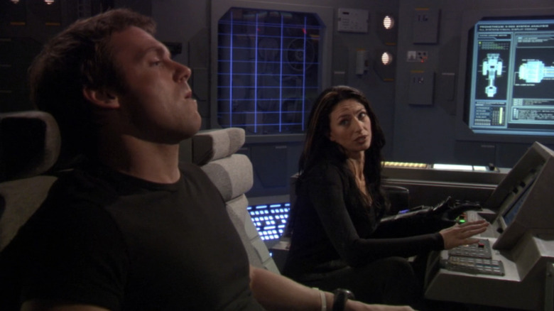 Claudia Black's Vala Mal Doran melihat ke seberang Michael Shanks 'Daniel Jackson saat duduk di pusat kontrol di Stargate SG-1