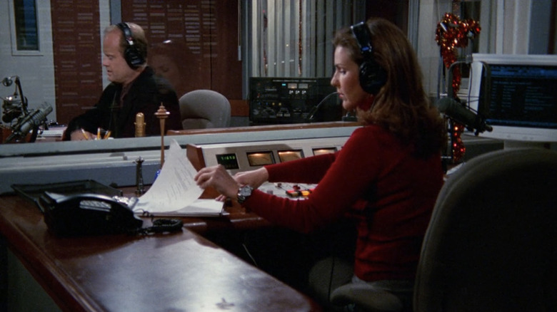 Peri Gilpin's Roz sits at in the control room at the KACL radio station while Kelsey Grammer's Frasier can be seen through the glass in Frasier