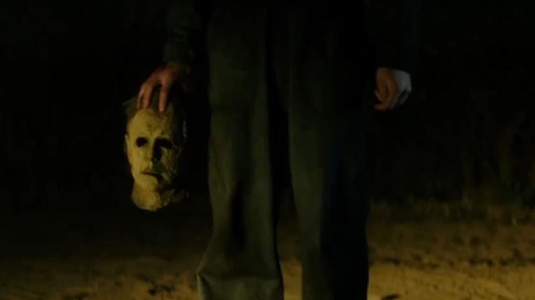 Someone mostly off camera holding the Michael Myers mask in Halloween Ends