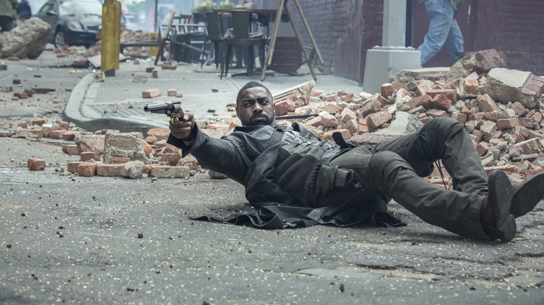 Idris Elbe in the role of rolend lying on the ground, shooting from the pistol in the movie of the dark tower