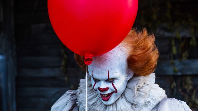 Pennywise (Bill Skarsgard) does that horrible crossed eye thing under a red balloon in It Chapter One