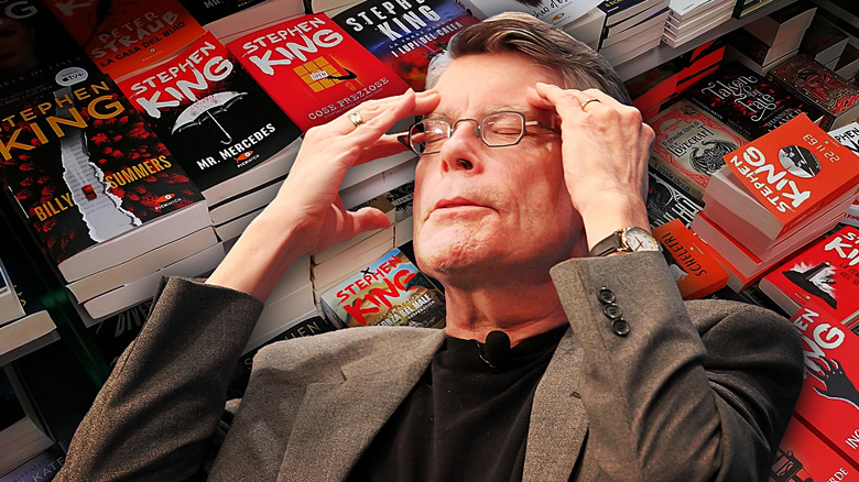 Stephen King looking exasperated with a bunch of his books behind him