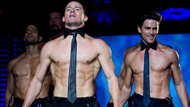 Shirtless tie-wearing men on stage