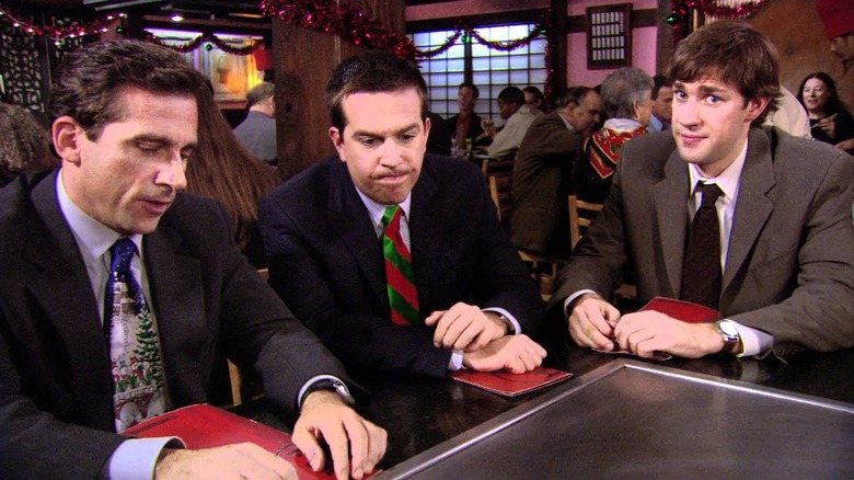 Michael Scott, Andy Be RNA RD, and Jim Halpe RT sitting on the Benihana table, with Jim makes AWKWA face in The Chep on the Office