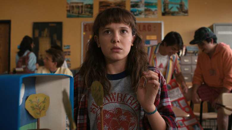 Millie Bobby Brown in eleven sitting in the chapter raises her hand on strange things