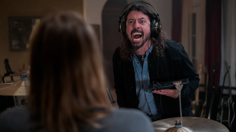 dave grohl with sharp teeth and headphones on yelling at his drummer