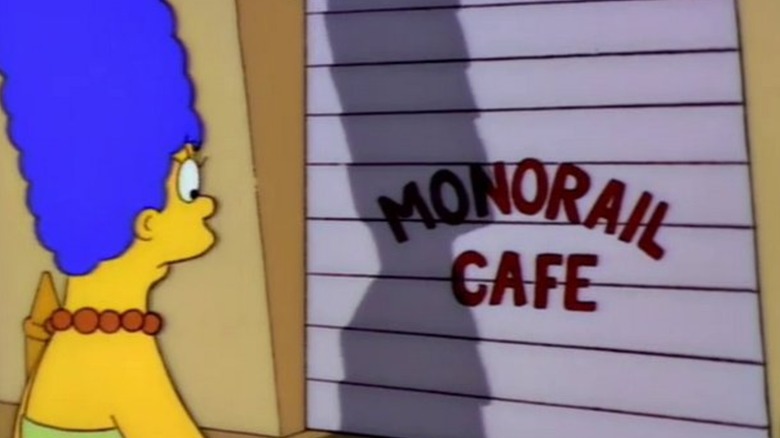 Marge looks at a shuttered storefront labeled Monorail Cafe in The Simpsons