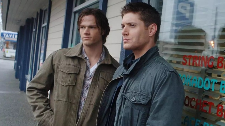 Sam and Dean Winchester stand on sidewalk