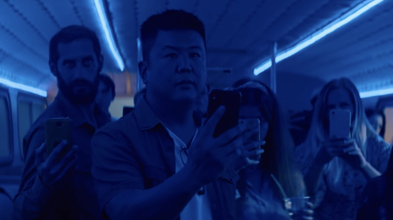 a group of people with cell phones up on a blue-lit vehicle