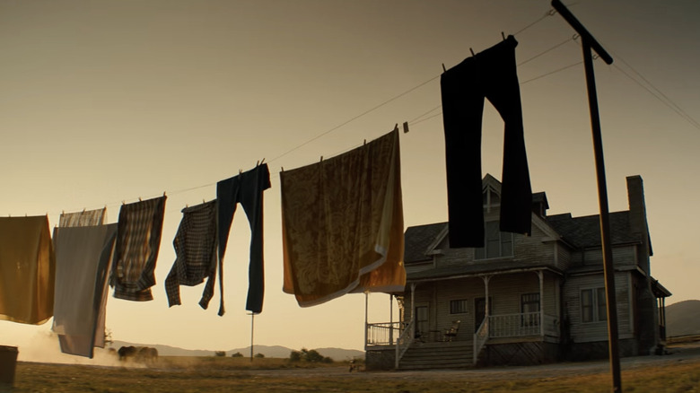 a house in shadow of a setting sun with a full clothesline in front of it