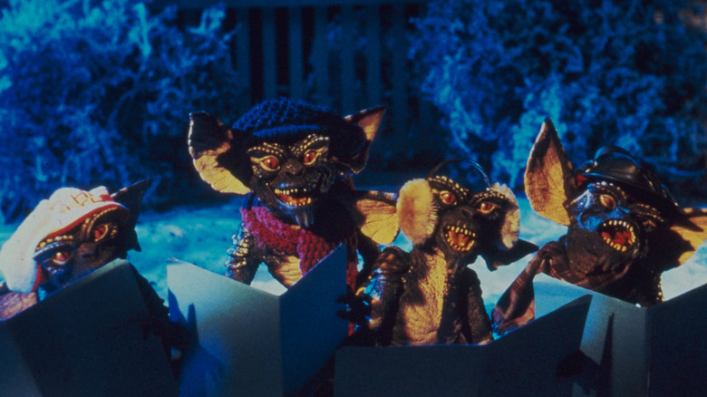 A group of Gremlins singing Christmas carols on a snowy night while wearing winter clothing in "Gremlins" (1984)