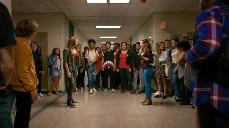 Peyton List's Tory Nichols and Mary Mouser's Samantha Larusso facing off in a hallway on Cobra Kai