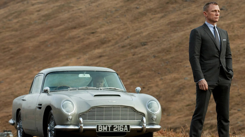 James Bond (Daniel Craig) stands in front of his Aston Martin DB5 in Skyfall