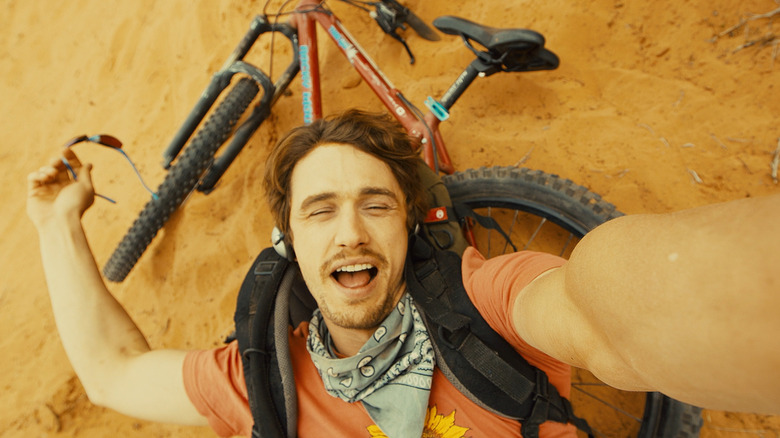 James Franco as Aron Ralston in 127 Hours lying back on his bike on the ground