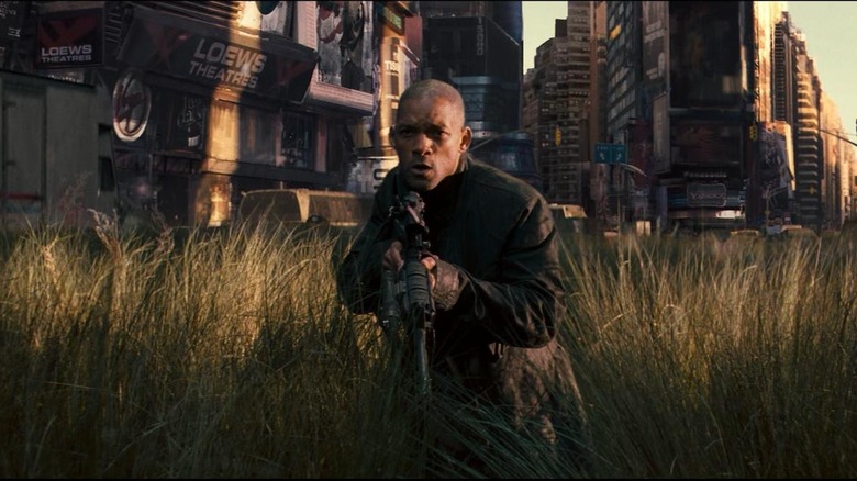 Will Smith in I Am Legend holding a gun in a field in Times Square