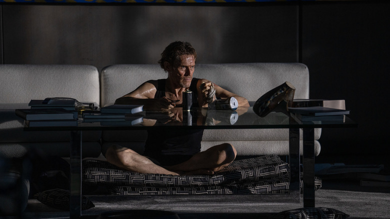 Willem Dafoe as Nemo in Inside looking pensive by a coffee table