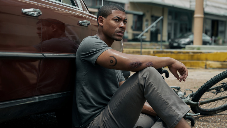 Aaron Pierre as Terry Richmond leaning against a car in Rebel Ridge