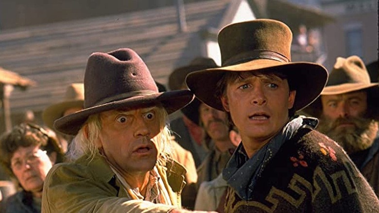 Doc Brown and Marty McFly each wearing cowboy hats and looking shocked at something off-screen to their left in Back to the Future Part III