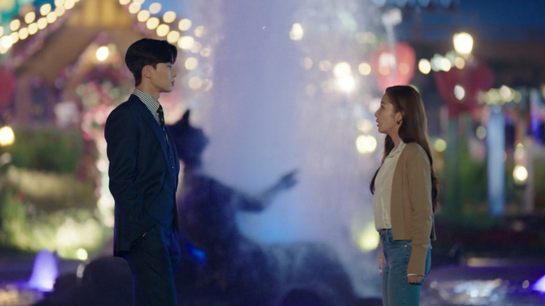 Lee Young-joon (Park Seo-joon) faces Kim Mi-so (Park Min-young) by a fountain on What's Wrong with Secretary Kim