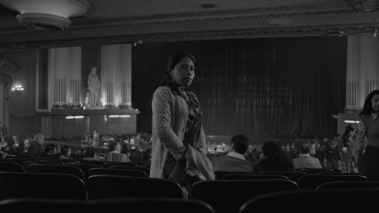 Yalitza Aparicio as Cleo Gutiérrez standing in the middle of a movie theater in Roma