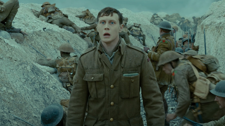 George MacKay as Lance Corporal Schofield stands in a trench in 1917