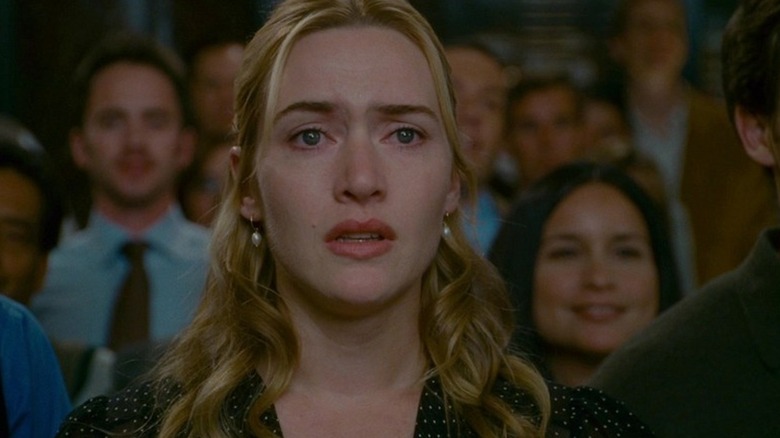 Kate Winslet's Iris stands in a crowd of people, looking emotional, in The Holiday