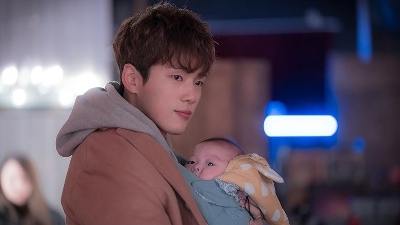 Kang Dong-goo (Kim Jung-hyun) holds a baby in Welcome to Waikiki