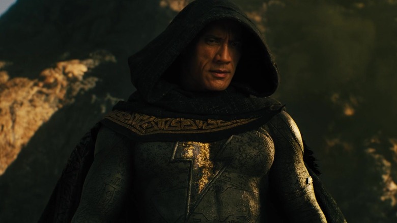 Dwayne Johnson as Black Adam, wearing a cloak and looks down from into a mountain range