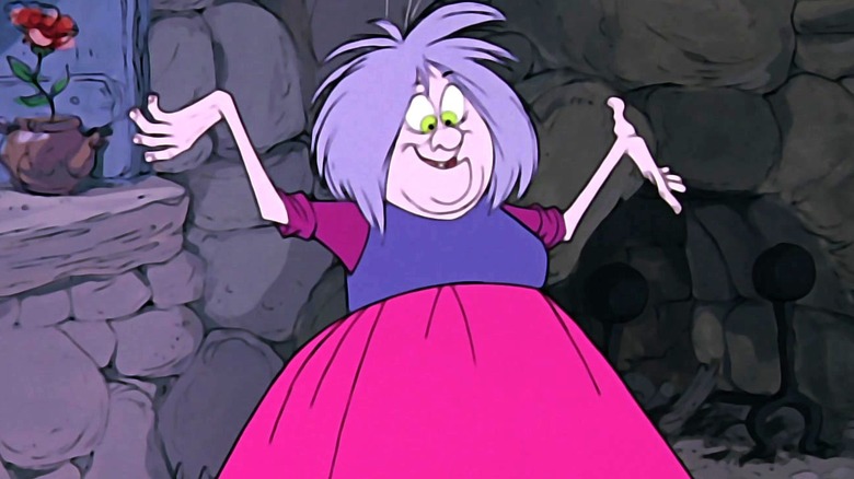 Madam Mim smiles and throws her hands up in the air while wearing a purple and pink dress as she stands near a window in her home in The Sword in the Stone