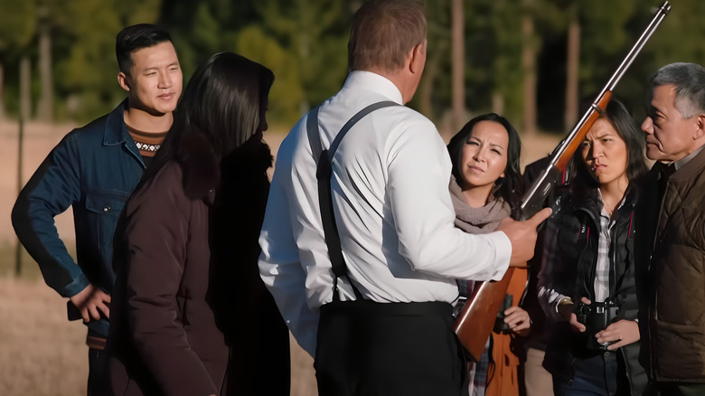 John Dutton holding a rifle around Asian tourists on Yellowstone