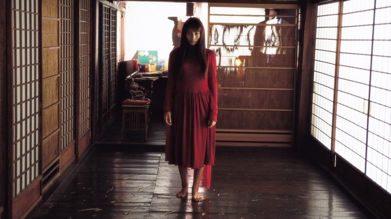 A woman in a red dress stands in an empty hall