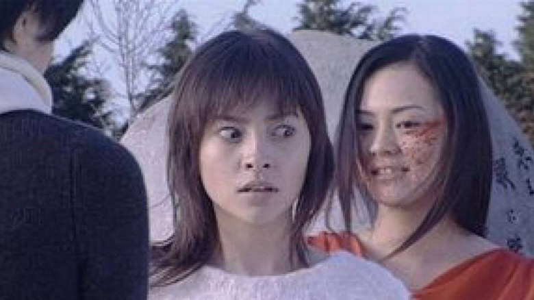 A blood-splattered girl appears behind a terrified woman